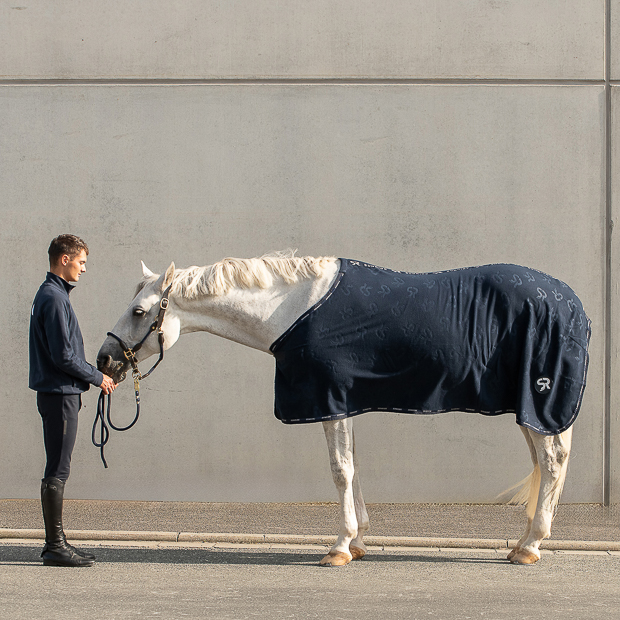 sunride abschwitzdecke wellington blau auf pferd und daneben sein reiter reiter mit seinem pferd mit abschwitzdecke wellington blau von sunride