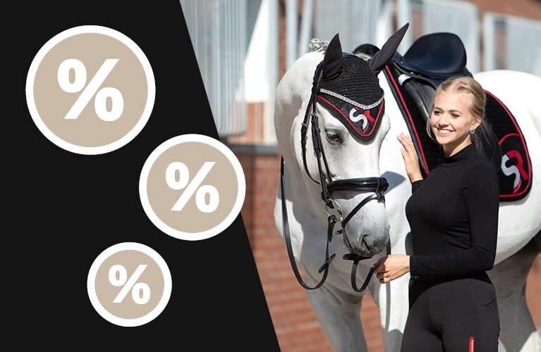 Eine Reiterin steht neben einem Pferd mit schwarz roter Schabracke und passender Fliegenhaube mit SR Logo im Hintergrund ist ein Stall