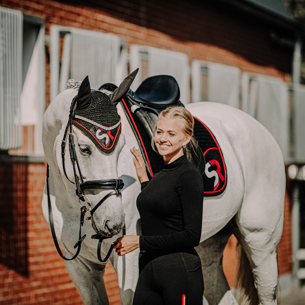 dressage saddle pad red black breathable with fur and matching earnet in a set on horse set of breathable dressage saddle pad red and black exclusive line with fur on withers and matching earnet on a horse with rider