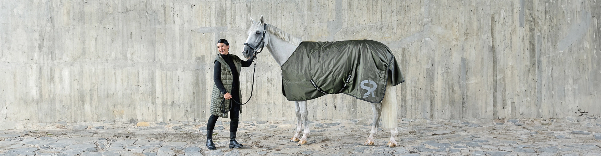 Winterdecke Ein Reiter steht einem Pferd gegenüber Das Pferd trägt eine dunkelgrüne Decke von Sunride Liverpool Modell