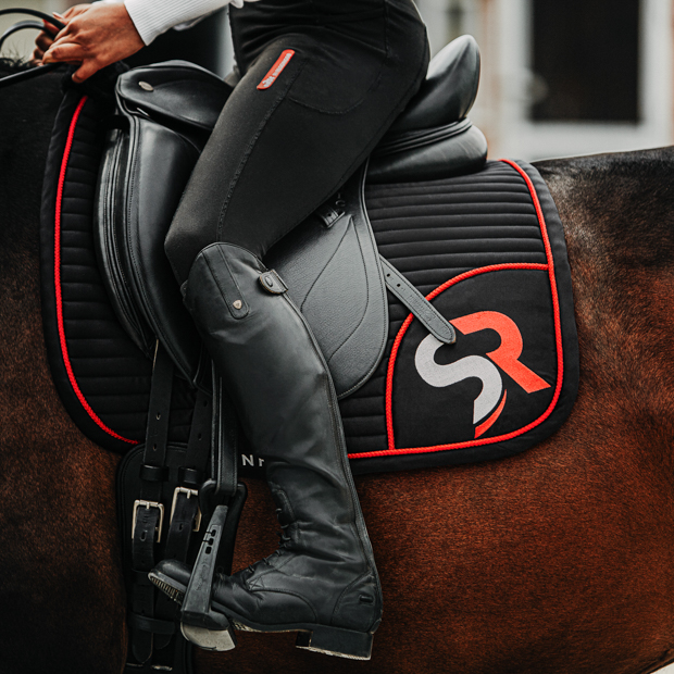 dressage saddle pad red black breathable with fur on horse breathable dressage saddle pad red and black exclusive line with fur on withers under saddle on a horse