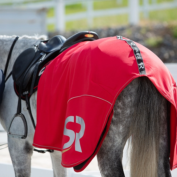 Abschwitzdecke Boston von Sunride Nahaufnahme eines gesattelten Pferdes mit einer roten Abschwitzdecke Boston von Sunride über der Kruppe