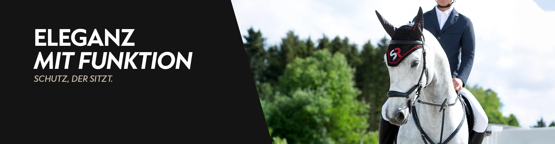 Ein Pferd mit roter Fliegenhaube und Reiter im Hintergrund sind grüne Bäume 