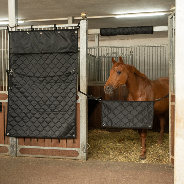 schwarzer boxenvorhang fuer den stall mit eingearbeiteten haeken und oesen und strippen zur aufbewahrung von sunride an der box im stall befestigt