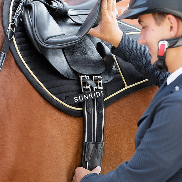 black silver stud guard girth hickstead on saddle elastic black leather stud guard girth hickstead with silver mounting by sunride on a saddle on horse